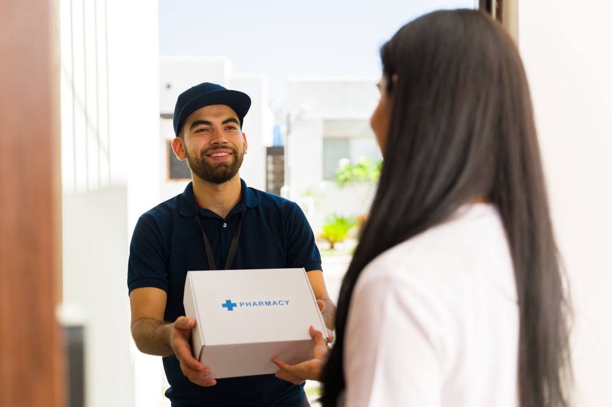 Courier handing a box of prescription medication to a patient at their front door